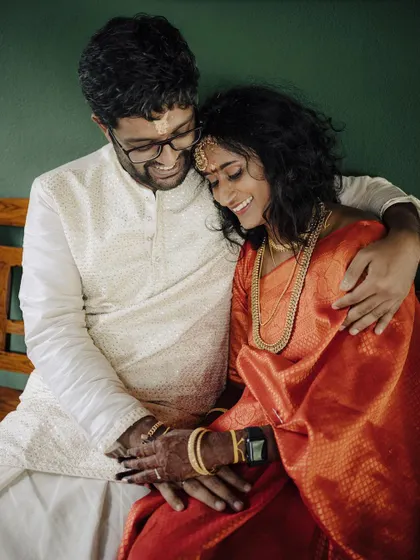 A tender moment shared on a bench. The groom's embrace and their gentle smiles create a portrait that is both intimate and heartwarming, capturing the quiet comfort they find in each other.