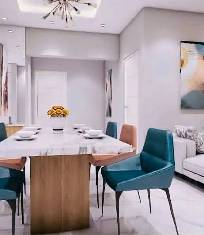 A vibrant and contemporary living and dining space. The design uses bold artwork and colorful dining chairs to create a lively atmosphere, balanced by a neutral sofa and clean lines.