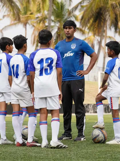 A BFC youth coach instructs a group of young players, providing them with tactical knowledge and encouragement.