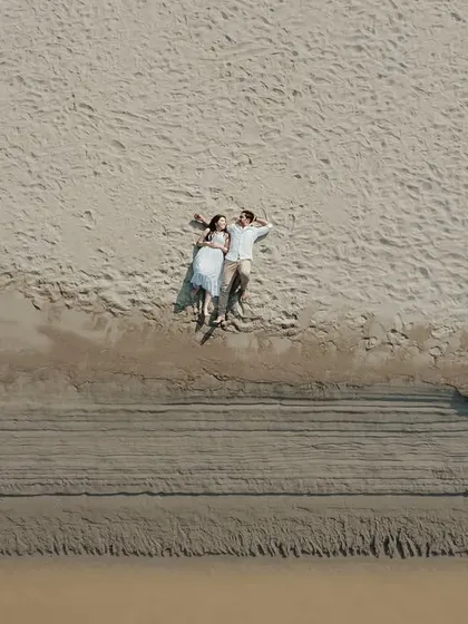 A stunning top-down drone shot of a couple lying on a sandy beach, creating a unique and epic pre-wedding photograph.