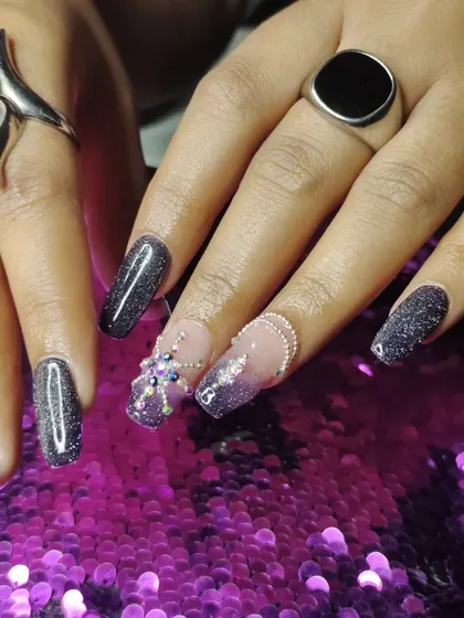 A close-up of the intricate 3D spider-like rhinestone design on a black glitter base.