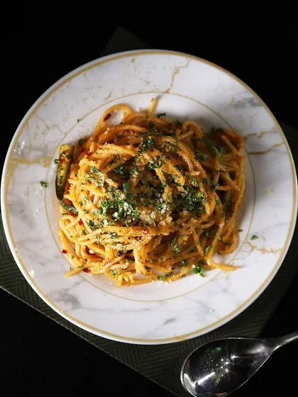 An overhead view of our perfectly plated Aglio Olio Spaghetti. The simplicity of the dish allows the quality of the fresh pasta and fragrant garlic and herbs to shine through.