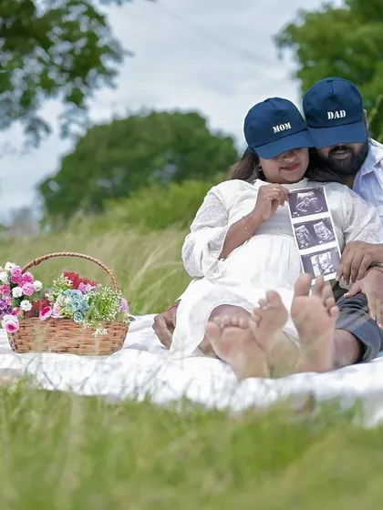 A casual and cute outdoor announcement. The couple uses their caps and the sonogram pictures to share their happy news in a relaxed picnic setting.