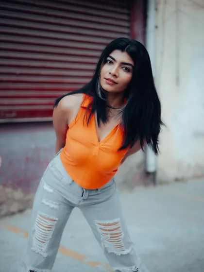 A full-length shot of a model in a casual but stylish outfit. The urban background and her relaxed pose are perfect for a street style lookbook.