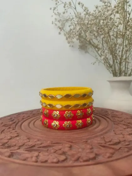 A bright and sunny set of handmade bangles in yellow and red. These are decorated with mirror work and floral sequin patterns, perfect for a Haldi or Mehendi function.