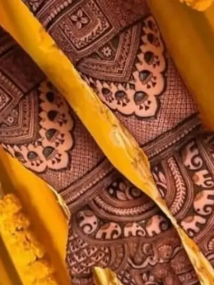 A close up view of a design rich with peacock motifs and traditional Indian patterns. The yellow marigold background adds to the festive wedding feel.