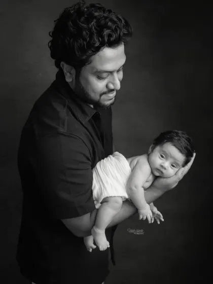 A powerful black and white portrait of a father holding his newborn. The dramatic lighting creates a beautiful, artistic image.
