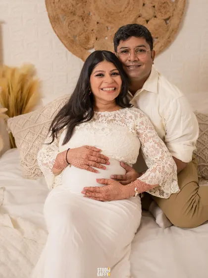 A happy couple portrait, with both parents' hands lovingly placed on the baby bump.