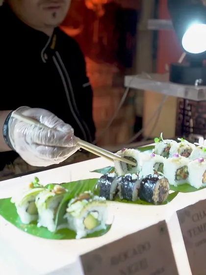 A chef at our sushi station, using chopsticks to place a delicate garnish on a roll. This close-up highlights the precision and artistry required for creating perfect sushi.