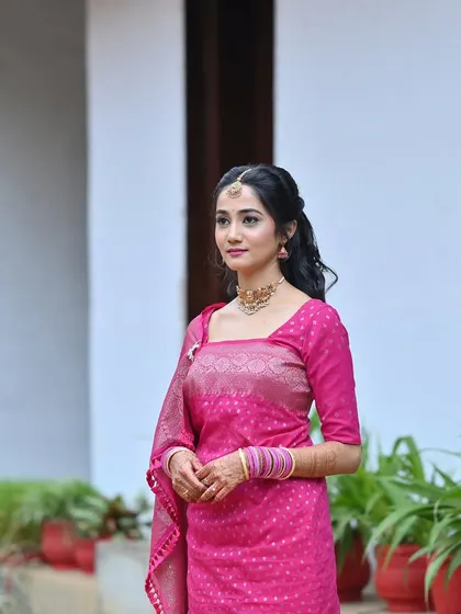 A full-length shot of the bride's Oorkuduva outfit. The simple makeup and hair complement the vibrant pink saree.