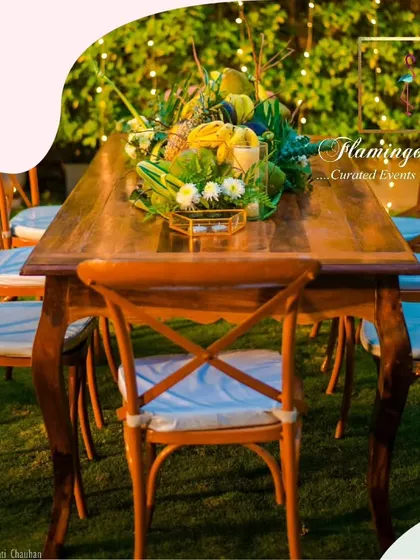 Another view of the elegant sit-down dinner setup, with the long wooden table and cross-back chairs creating a sense of communal celebration in the beautiful backyard.