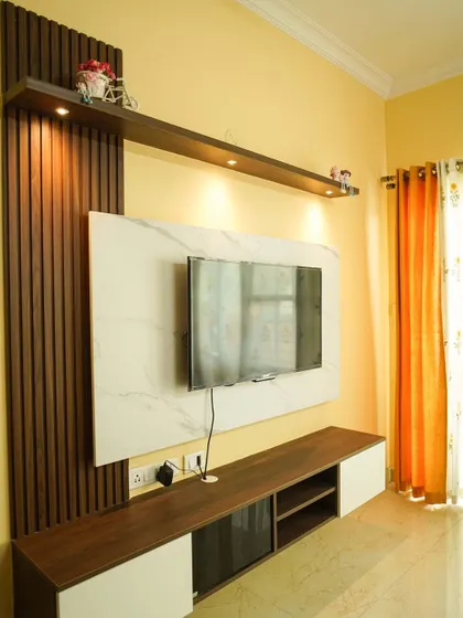 Another view of the TV unit from the Neeraj project, showing the balance between the white console and the warm wood paneling.