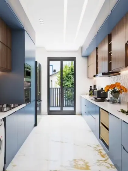 This galley kitchen combines dusty blue and wood-grain cabinets for a modern yet warm aesthetic. The layout leads to a balcony, providing excellent ventilation and natural light for the entire space.