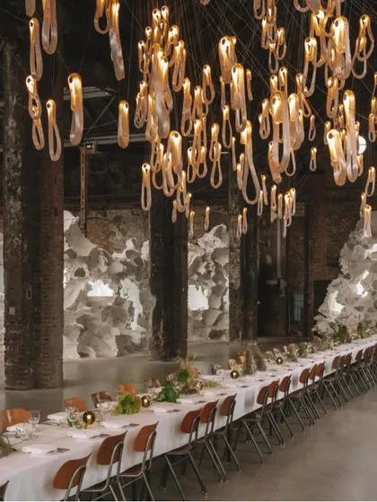 A closer view of the Bocci 87 chandelier over a dining setting. The stretching technique used to form these elegant loops is visible, and the tiny air bubbles within the glass create a beautiful pearlescent effect.