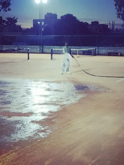 A wide shot of the courts being watered under the lights, showing my commitment to quality around the clock.
