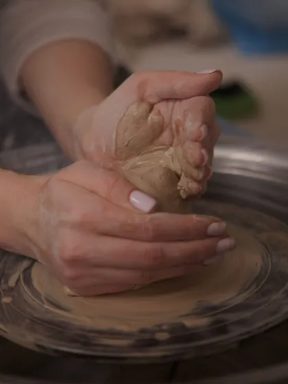 The very first step: centering the clay. A potter's hands work to force the lump of clay into the exact center of the wheel, a foundational skill for throwing any balanced piece.