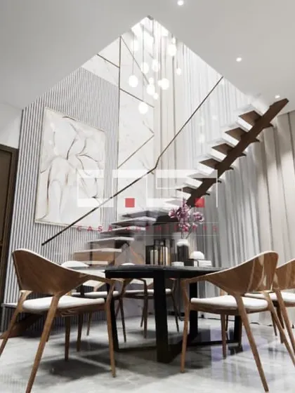 A low-angle view of the dining area under the floating staircase, emphasizing the vertical space and the modern, minimalist aesthetic.