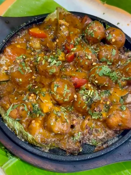 The sizzle is real! This close-up shows the rich, bubbling sauce coating the bondas, promising a fiery and flavorful bite.