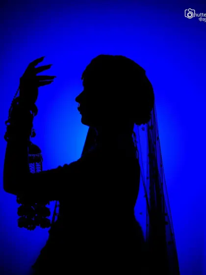 A creative silhouette of the bride against a bold blue background. This artistic approach to bridal portraiture creates a mysterious and visually striking image.