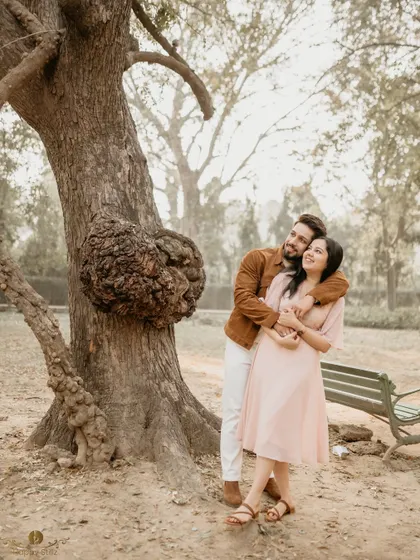 A classic portrait of a couple embracing by a large tree. Their happy expressions and the natural setting make this a timeless and heartwarming pre-wedding photo.