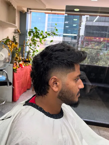 A classic modern mullet with a mid-fade. The top is styled with texture and volume, while the back is left longer for that signature mullet look.