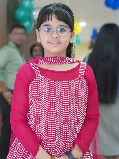 A simple and sweet portrait of a young girl in a pink dress, smiling for the camera.