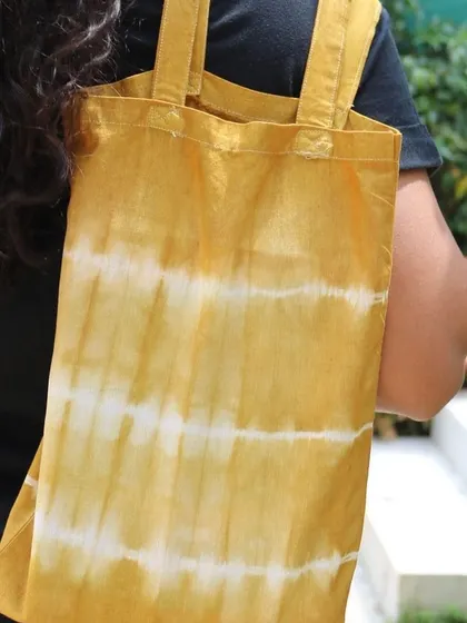 A participant's finished tote bag, dyed with marigold petals to create a lovely yellow striped pattern.