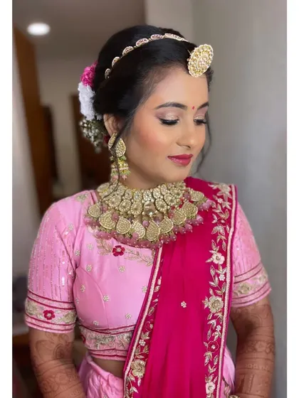 A classic bridal hairstyle. The neat bun adorned with fresh flowers adds a touch of traditional beauty to her overall look, ensuring she is picture-perfect from every angle.