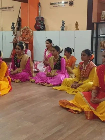 Students in colorful costumes sit patiently for their turn during the Prayag Sangeet Samiti exams.
