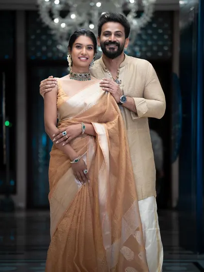 A classic portrait of the couple. The bride's Victorian-style choker adds a touch of modern elegance to her traditional saree.
