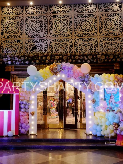 A welcoming entrance for a pastel-colored carnival theme, with a ticket booth prop, a Ferris wheel, and a beautiful balloon arch.