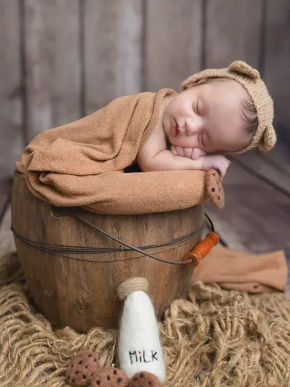 The full 'cookies and milk' bear setup, with the baby looking cozy and content in a rustic bucket.