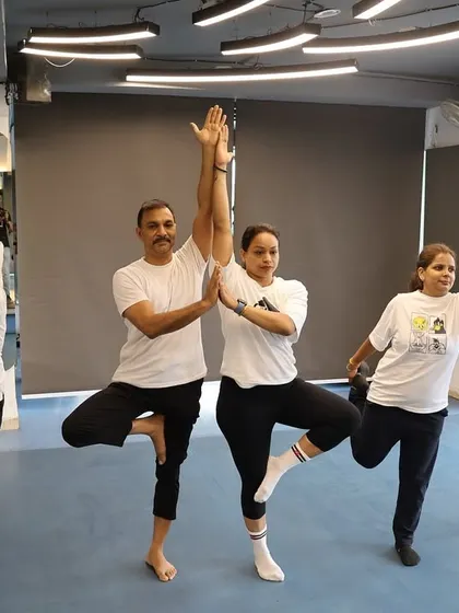 A group of members holding a balancing yoga pose, showing the collective focus and energy of the class.