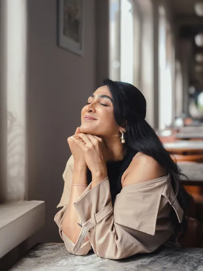 A serene moment from the 'Bonsoir' series. The off-shoulder styling of the trench coat and delicate pearl earrings create a soft, romantic, and fashionable look.