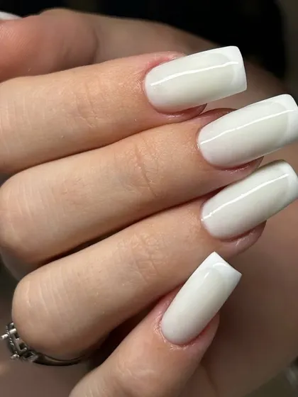 A modern take on the French manicure with a milky white overlay on long, square-shaped extensions. This creates a soft, blended look instead of a harsh line.