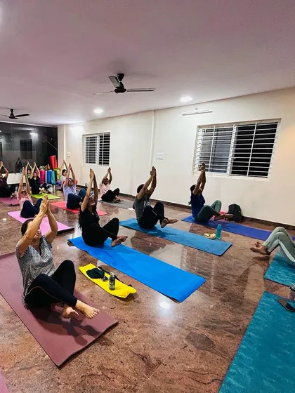Students engaging their core with Navasana, or Boat Pose, during an evening class. Core strength is fundamental to a stable and safe yoga practice.