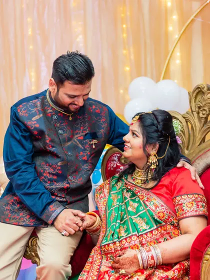 A tender moment between the couple during their traditional baby shower. The rich colors of their outfits and the festive decor create a vibrant and celebratory atmosphere.