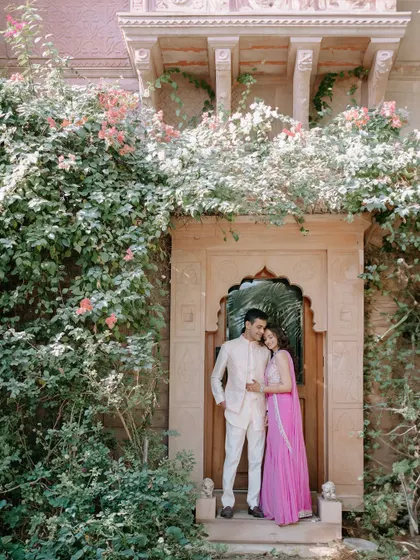 Kanav and Saloni framed within a beautiful arched doorway covered in flowering vines. This shot perfectly combines the grandeur of the location with a touch of natural romance.