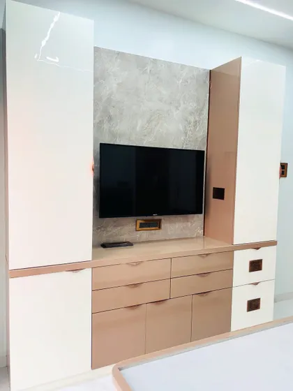 I designed this bedroom TV unit with a mix of high-gloss white and beige laminates for a subtle, elegant look. The unit provides a combination of drawers and cabinets for extensive storage.