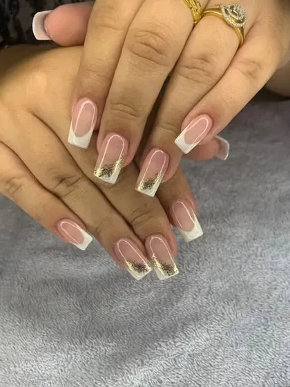A classic French manicure on square nails with encapsulated gold flakes at the tips.