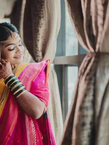 A candid moment of the bride adjusting her jewelry, bathed in beautiful window light.