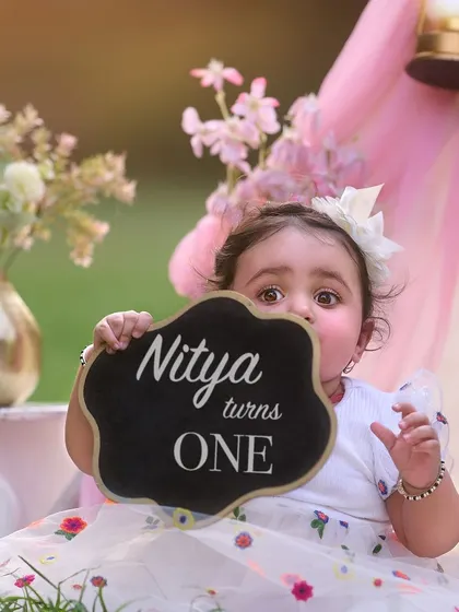 A little shy but oh so sweet. This first birthday portrait captures a tender moment as little Nitya celebrates turning one with a custom chalkboard sign and a beautiful floral teepee backdrop.