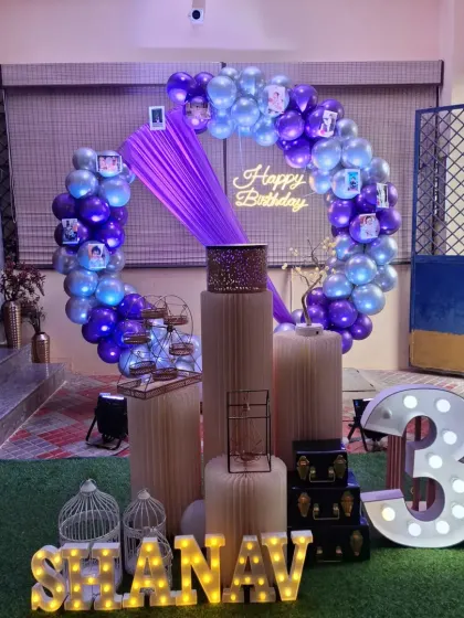The purple draping and photos clipped to the balloon ring add a personal and charming touch to this home birthday setup.
