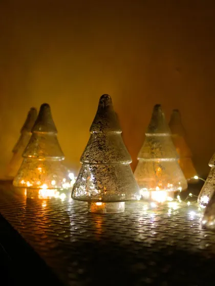 Small glass Christmas tree ornaments with fairy lights inside, adding a warm, magical glow to our space.