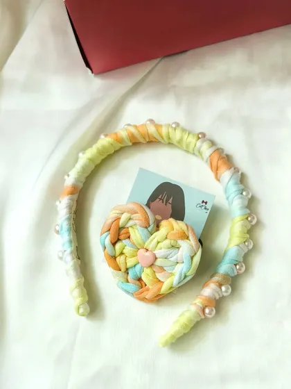 A pastel K-Pop princess braids headband with pearl details, shown with its matching heart hair tie.