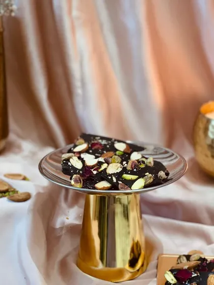 These Shahi Mewa Sheets are inspired by the rich Mewa culture of Jodhpur. They are made with the finest chocolate, cocoa butter, and a generous topping of roasted pistachios, almonds, and rose petals.