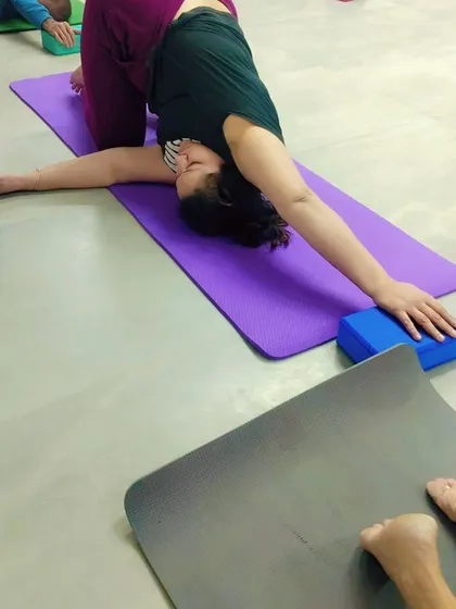 Here, a student uses a yoga block for support in Parivrtta Janu Sirsasana (Revolved Head-to-Knee Pose). This modification helps to gently open the side body and shoulders.