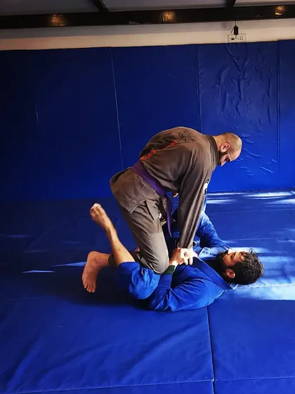 A coach demonstrates a guard pass while a student defends. This is how we learn through practice.