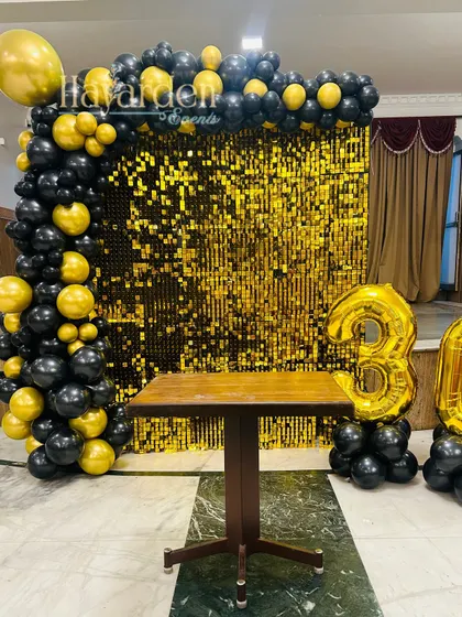 Celebrating a 30th birthday with a bang. This decor uses large gold foil '30' balloons, a gold sequin wall, and a black and gold balloon frame.