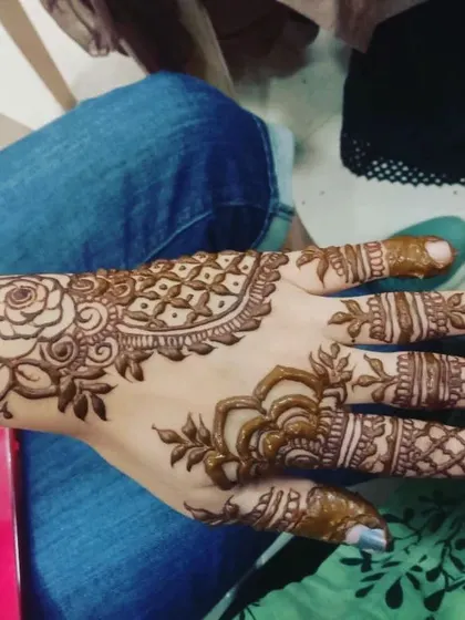 A beautiful example of a rose-centric design that trails along the side of the hand. This style is very elegant and photographs beautifully, making it a favorite for parties.